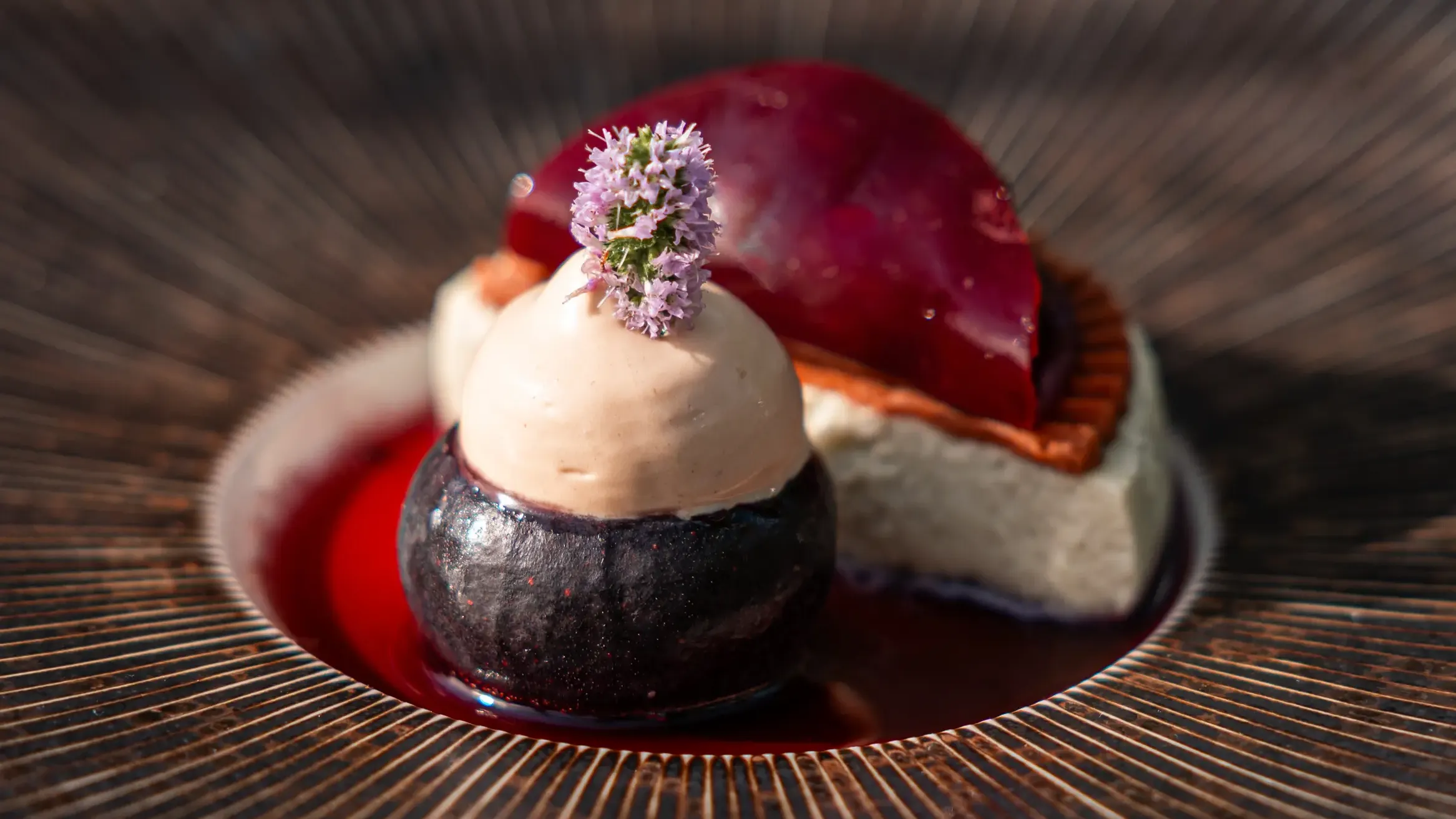 Un dessert composé d'une boule de glace, d'une purée de fruits et d'une garniture rouge dans un bol en céramique